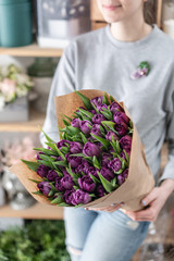 Young beautiful woman holding a spring bouquet of purple tulips in her hand. Bunch of fresh cut spring flowers in female hands