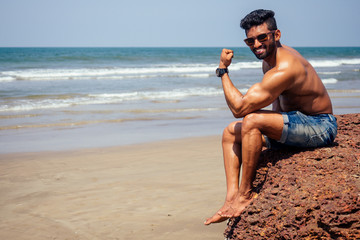 Handsome muscular dark haired surfer athletic muscular and healthy black man on beach during summer morning warm up ocean india sea Goa vacation