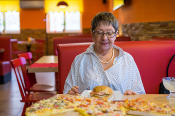 An elderly lady ordered fast food in a cafe restaurant. Doubt overwhelms her - because a hamburger entails excess weight.