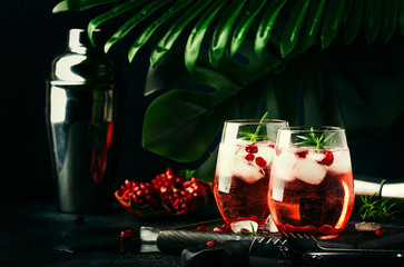 Red cocktail vodka pomegranate juice, with ice and rosemary, bar tools, blue bar counter background, top view