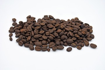 Side view of scattered coffee beans on a white background