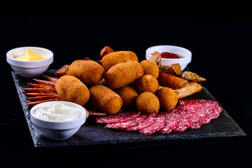 cheese balls and salami sliced on a dark background