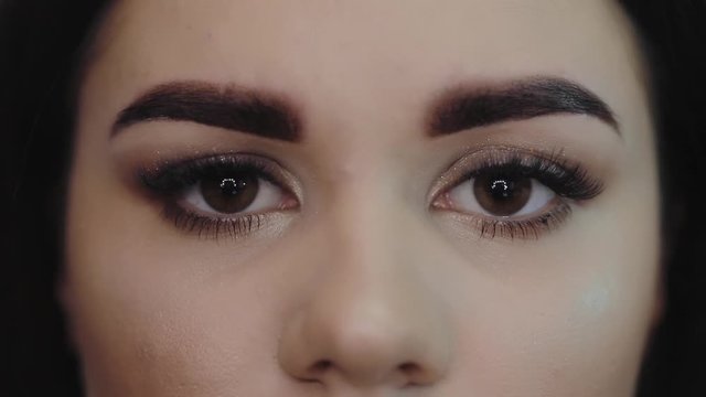 Young girl tweezing her eyebrows in a beauty salon. Eyebrows closeup, look into the camera