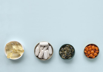 Pills, tablets and capsules and a bottle on a blue background. Copy space for text.