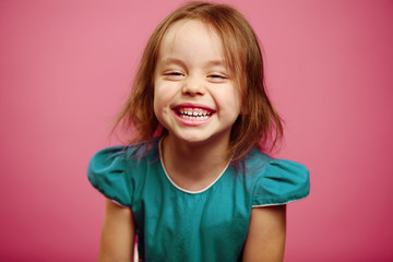 Adorable little girl laughing on pink isoalted.
