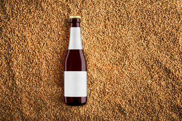 Brown beer glass bottlle mockup on wheat grains.