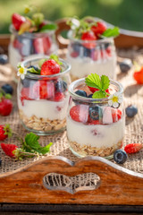 Healthy oat flakes in jar with yoghurt and berries