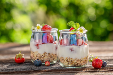 Tasty oat flakes in jar with yoghurt and berries