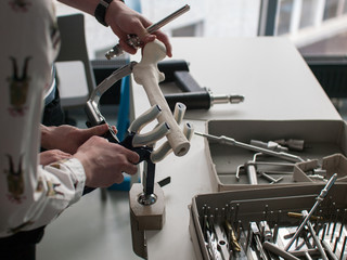 Young doctors and medical students train with instruments and plastic bones for orthopedic...