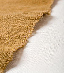Burlap lying on a white wooden table. Preparation for the designer. Plenty of room for text and photo.