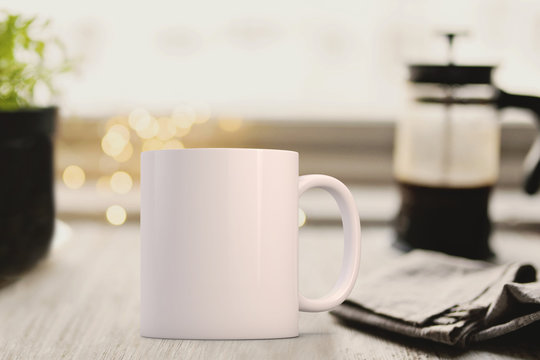 White mug infront of a cafetier and newspaper. Perfect for businesses selling mugs, just overlay your quote or design on to the image.