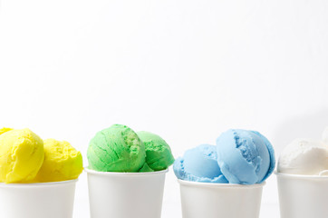 Ice cream with different flavours in paper cups against white wall.Concept of summer sweet menu