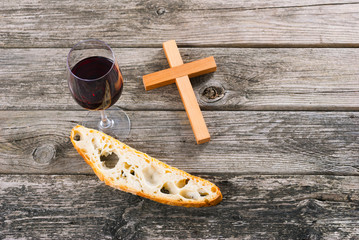 wooden cross and red wine with a slice of bread on old wood table