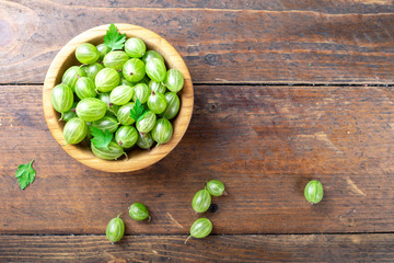 Ripe green gooseberries in a wooden bowl.