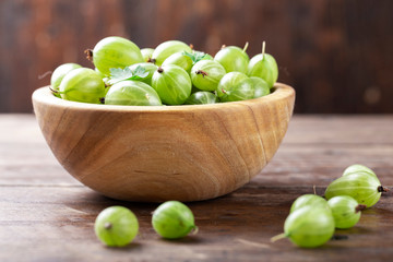 Ripe green gooseberries in a wooden bowl.