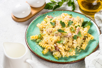 Pasta carbonara with zucchini in craft plate on white. 
