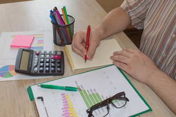 Businessman writing in a notebook. Close up view of bookkeeper or financial inspector hands making report, calculating or checking balance