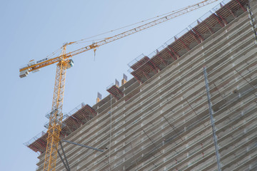 Big industrial tower crane with unfinished high raised building