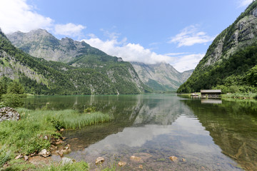 Fototapeta na wymiar Konigssee lake with clear green water, reflection, mountins and sky background, Germany