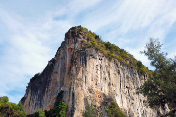 Majestic sheer limestone colorful mountain covered with tropical greenery on top in Krabi province in Thailand