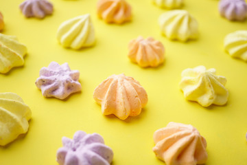 sweets background, dessert design. arrangement of colorful meringue cookies on yellow backdrop. minimal food concept