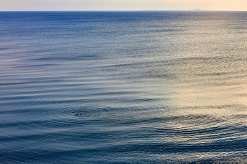 Idyllic seascape with soft morning color. The calm sea reflects the clear sky like a mirror. Blue sea background with rising sun