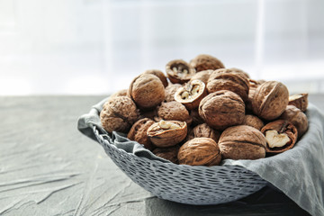 Bowl with tasty walnuts on grey table
