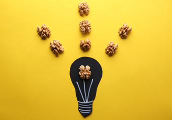 Light bulb with tasty shelled walnut on color background