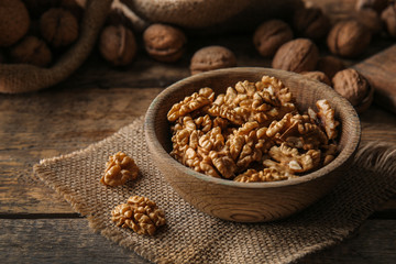Bowl with tasty walnuts on table
