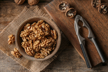 Bowl with tasty walnuts on wooden table