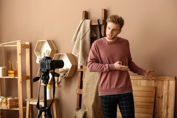 Young male blogger recording video in workshop