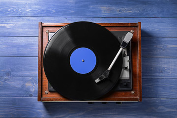 Record player with vinyl disc on wooden table