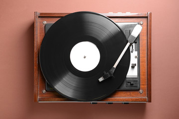 Record player with vinyl disc on color background