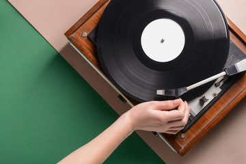 Hand of woman switching on record player with vinyl disc