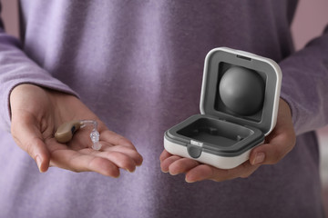Woman with hearing aid and box, closeup