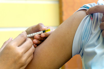 Doctors or nurses near the hands are vaccinating the patient using a syringe that is injected at the upper arm to receive medical treatment for injections with the patient. Vaccination against 