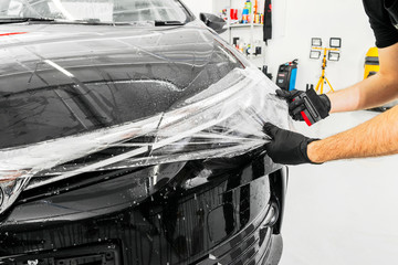 Car wrapping specialist putting vinyl foil or film on car. Protective film on the car. Applying a...