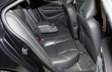 Clean after washing the rear passenger seats of matte black genuine leather inside the interior of an expensive sedan, preparation before selling the car.