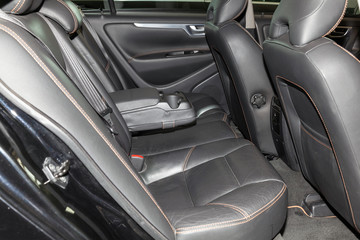 Fototapeta na wymiar Clean after washing the rear passenger seats of matte black genuine leather inside the interior of an expensive sedan, preparation before selling the car.
