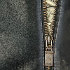 zip with bank notes out of the pocket of a leather bag of grey color. copyspace