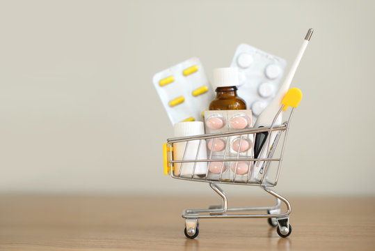 Shopping Cart Toy With Medicaments: Pills, Blister Packs, Medical Bottles, Thermometer Set. Health Care And Medicine Concept. Free Copy Space.