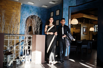 Lovely indian couple in love, wear at saree and elegant suit, posed on restaurant.