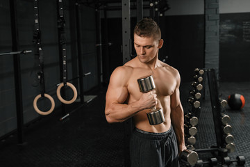 Fototapeta na wymiar Handsome power athletic man bodybuilder doing exercises with dumbbell