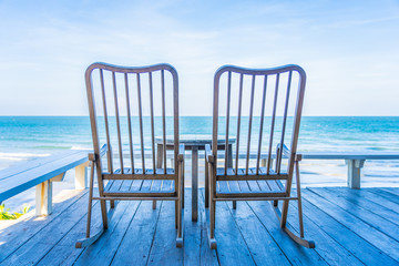 Empty wood chair and table at outdoor patio with beautiful tropical beach and sea