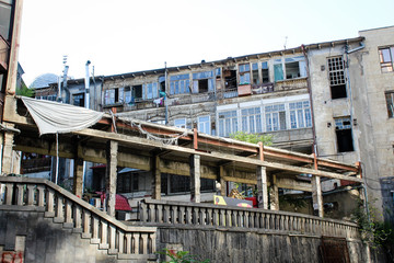 Naklejka premium Slums, old houses in Tbilisi, Georgia. Balconies, drying clothes. Ladder, wires, brown, gray. Capital.