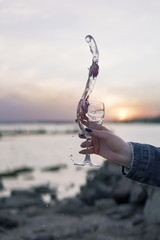 Naklejka na ściany i meble wineglass glass on the background of the sunset sea and roses wineglass