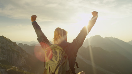CLOSE UP: Unrecognizable female hiker sits on a rock and outstretches her arms.