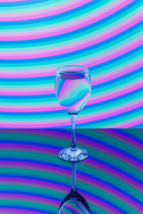 Wine glass with pink, blue, turquoise, orange, green, yellow neon stripes in the background.