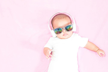 Asian baby girl wears white headphone and white shirt on pink background