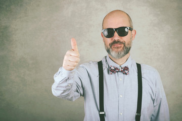 happy man with sunglasses and bow tie showing thumbs up